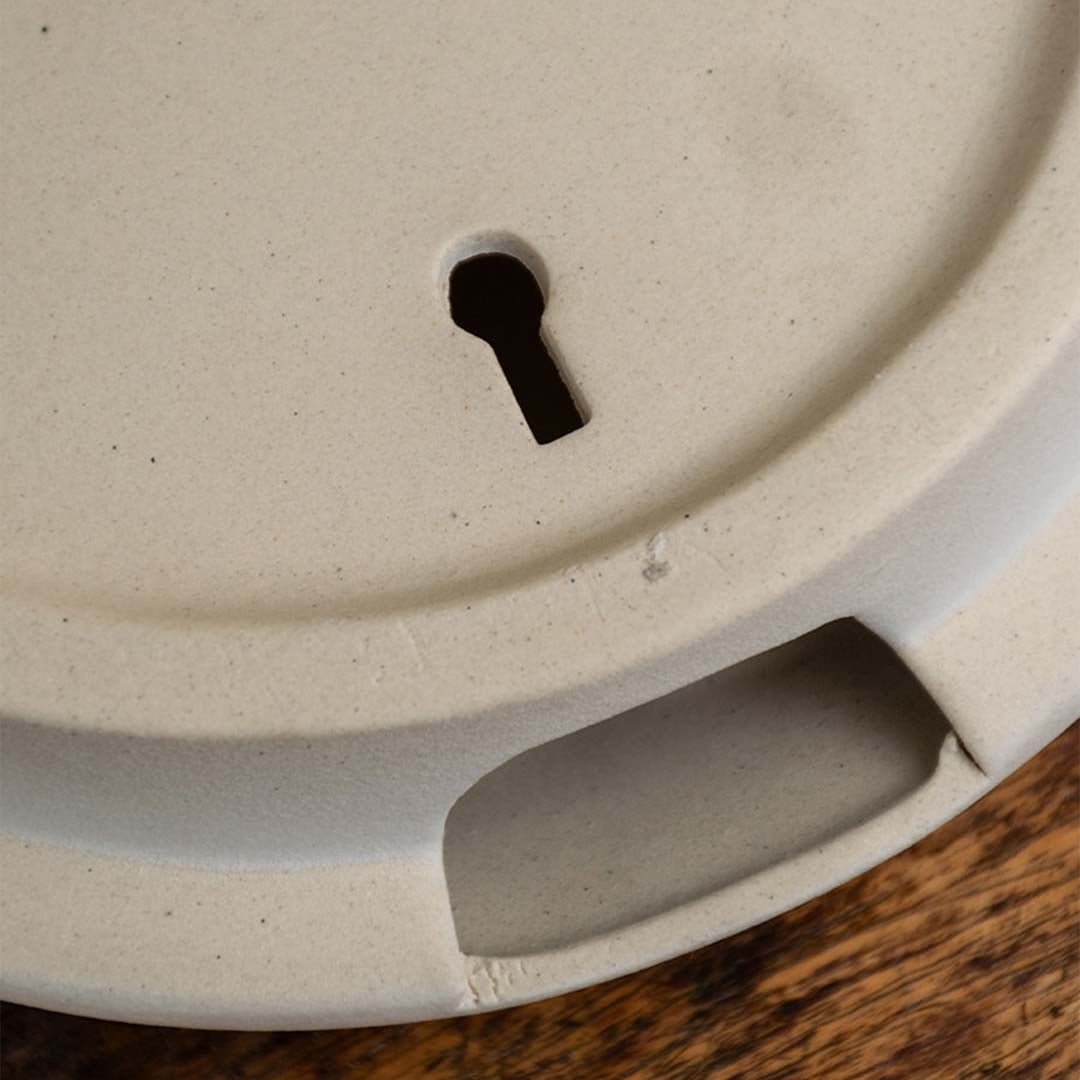 Closeup of the round white face sculpture vase showing its carved facial details and textured matte finish.