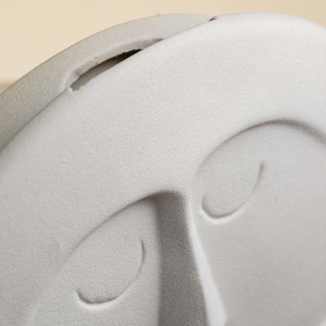 Detailed close view of the round white face vase showing the sculpted nose closed eyes and curved mustache design.