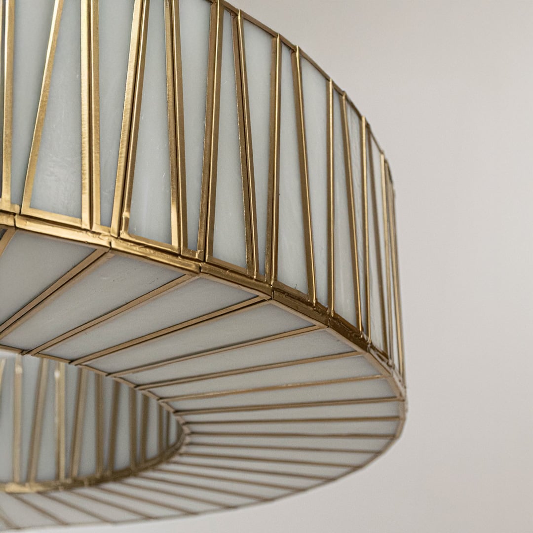 Close view of gold pendant light showing vertical bar texture and circular metal frame in elegant modern finish.