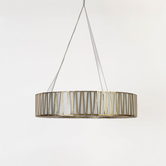 Gold drum pendant light shown in softly lit room without white background emphasizing warm ambient lighting effect.