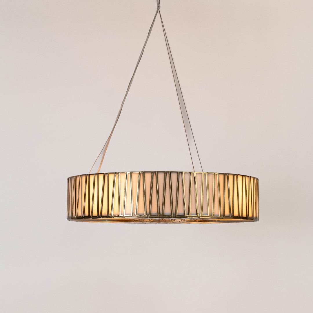 Contemporary gold wire pendant light with drum shape and vertical rods displayed clearly on plain white backdrop.
