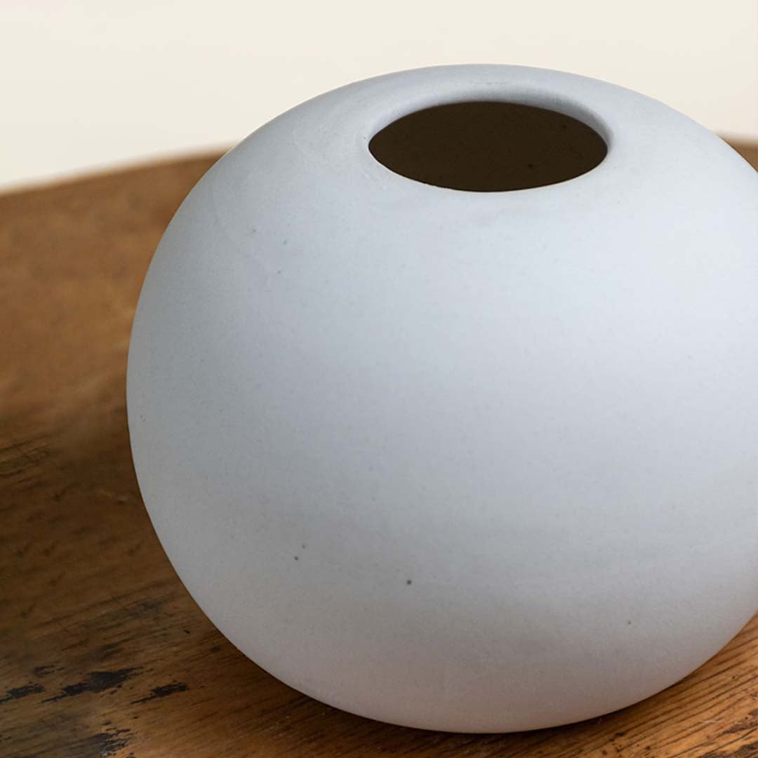 Closeup of white matte ceramic vase with soft rounded form and smooth texture highlighting modern craftsmanship and minimal styling.