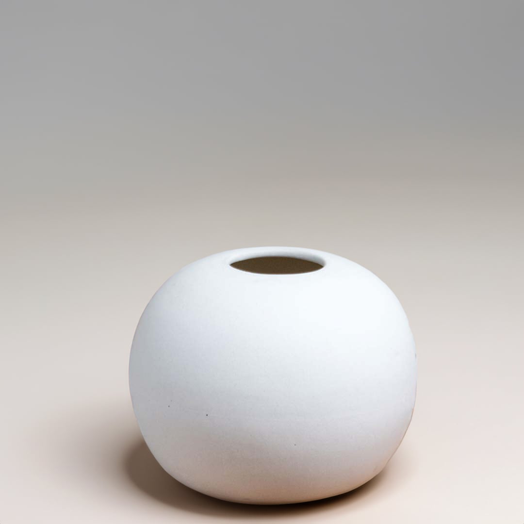 White matte ceramic round vase displayed on a neutral white background showcasing its minimal modern shape for clean decor presentation.