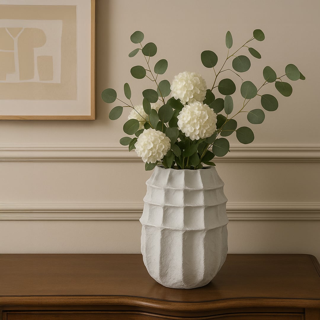 White sculptural ceramic vase with textured surface styled with white flowers on wooden table for elegant living room decor.