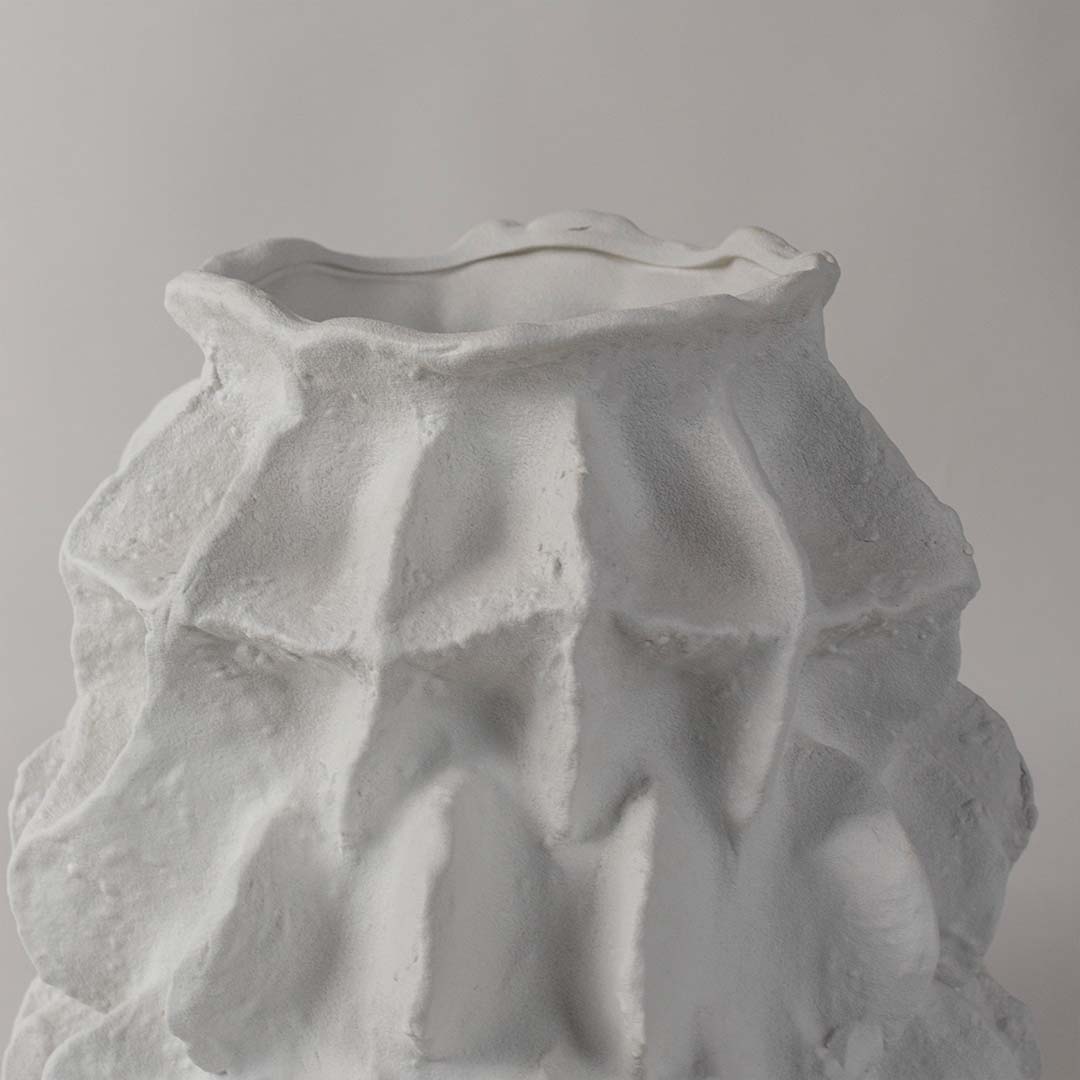 Closeup of white ceramic vase with handcrafted textured details and artistic sculptural design perfect for elegant home decor.