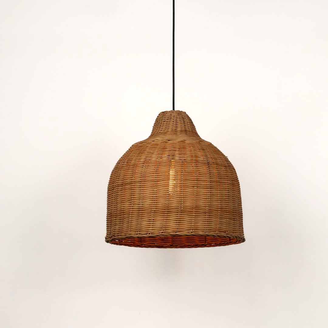 Brown rattan pendant light with dome shaped bamboo weave turned on glowing softly against plain white background.