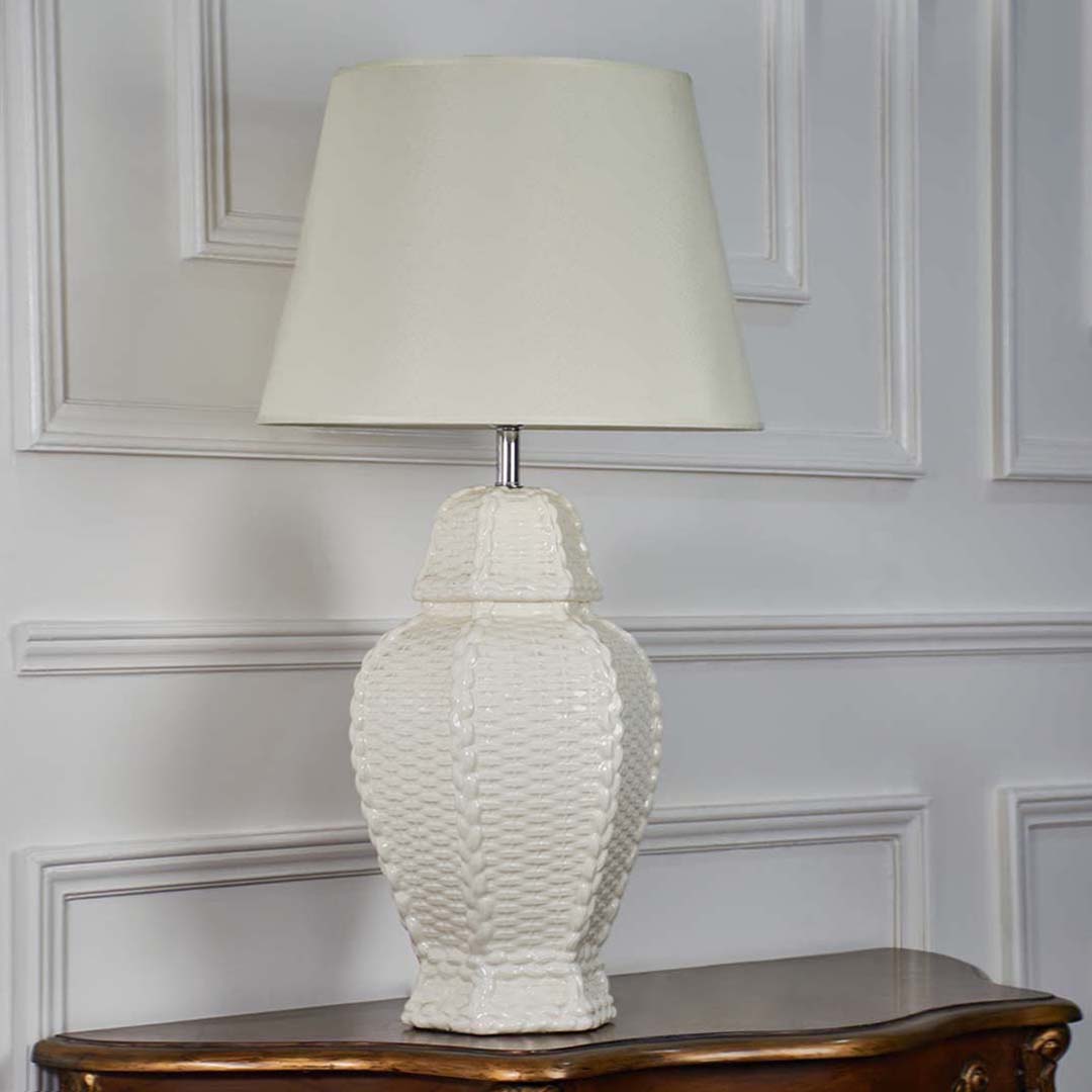 Elegant white ceramic table lamp with sculpted woven texture and cream shade standing out on a dark background for a luxurious decor feel.