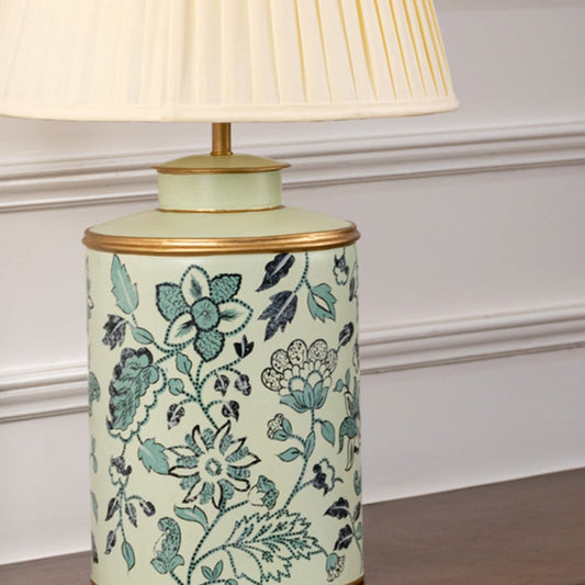 Closeup of mint green floral ceramic lamp base with golden rim and cream pleated shade showing intricate floral artwork.