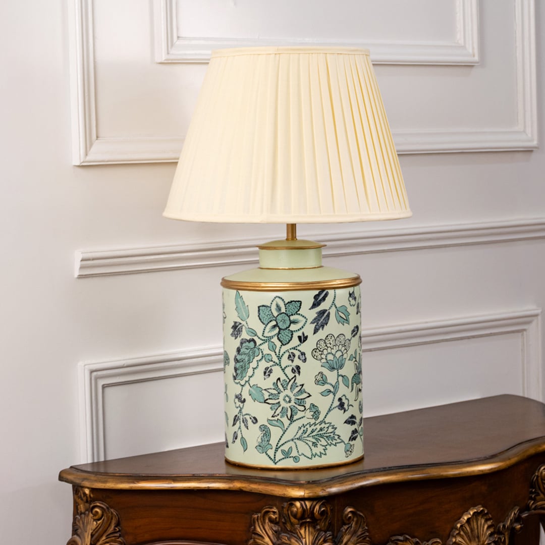 Mint green floral ceramic lamp with cream pleated shade turned off revealing floral detailing and matte golden trim.