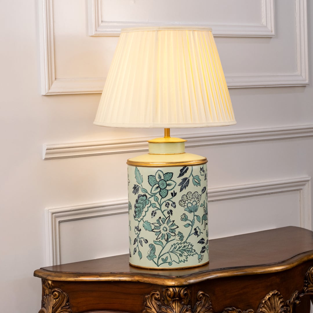 Mint green ceramic lamp with cream pleated shade glowing warmly featuring hand-painted floral patterns for refined home decor.