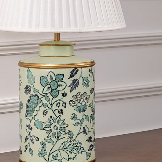 Closeup of mint green ceramic lamp base with white pleated shade showing hand-painted floral detailing and golden rim finish.