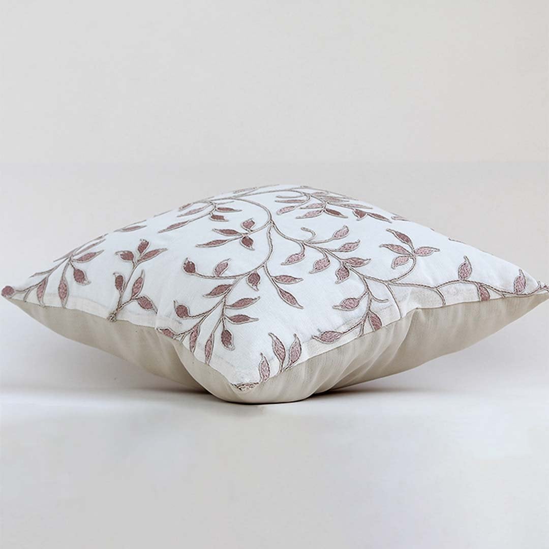 White cotton cushion cover featuring maroon botanical motifs shown at an angle providing a refined natural décor accent with a breathable soft and skin friendly fabric.