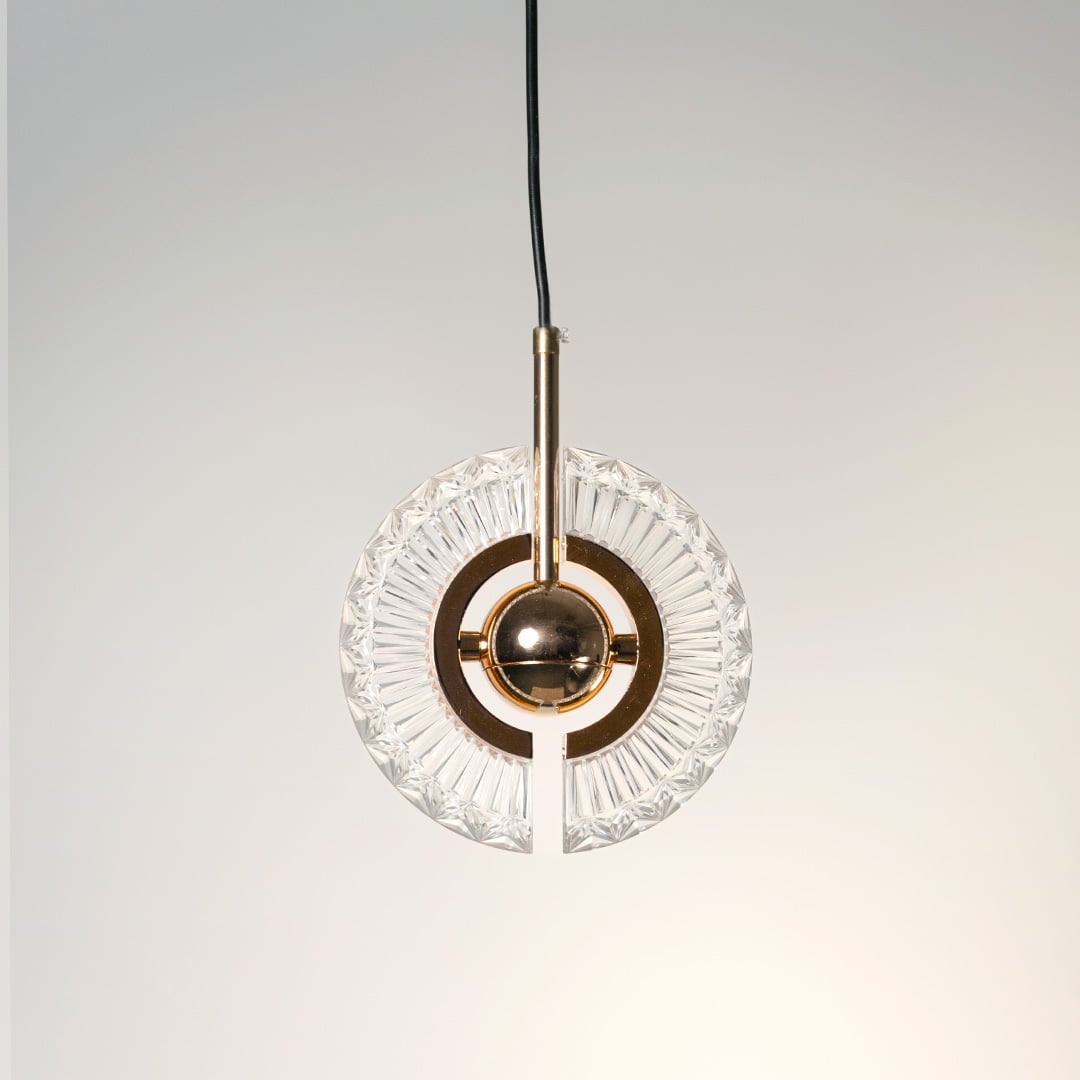 Crystal halo pendant light turned off with transparent crystal ring and gold sphere against white background for clean minimalist look.