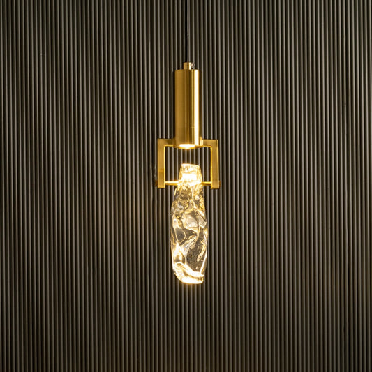 Gold metal wall light with clear textured glass tube glowing on black background creating elegant modern accent lighting for interior walls.