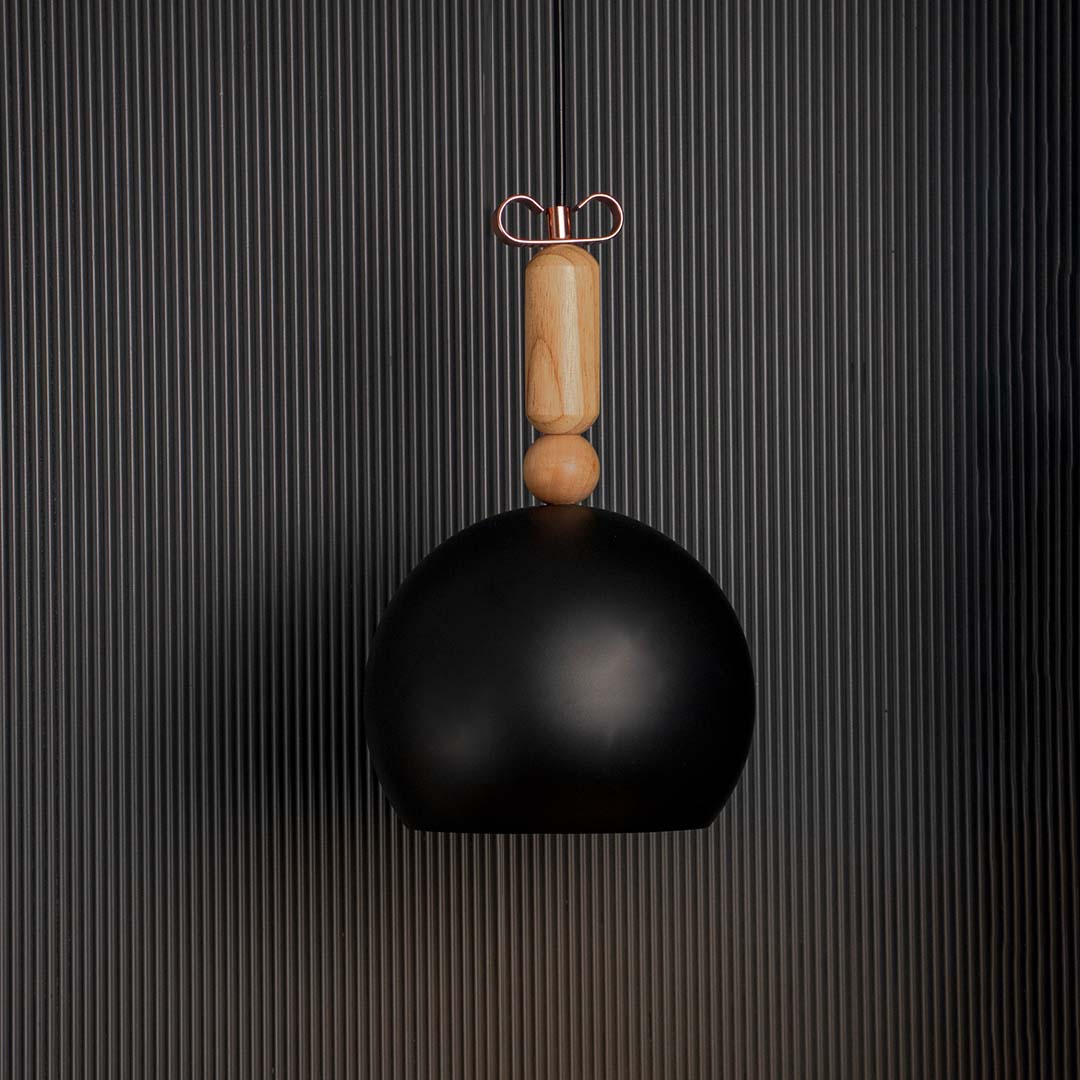 Black dome pendant light glowing warmly on black background ideal for dining kitchen and living room interiors.
