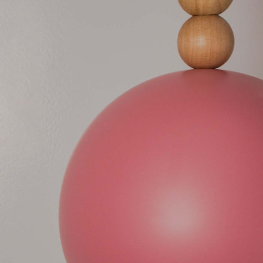 Closeup of terracotta dome pendant lamp with wooden accent highlighting smooth matte finish and stylish design.