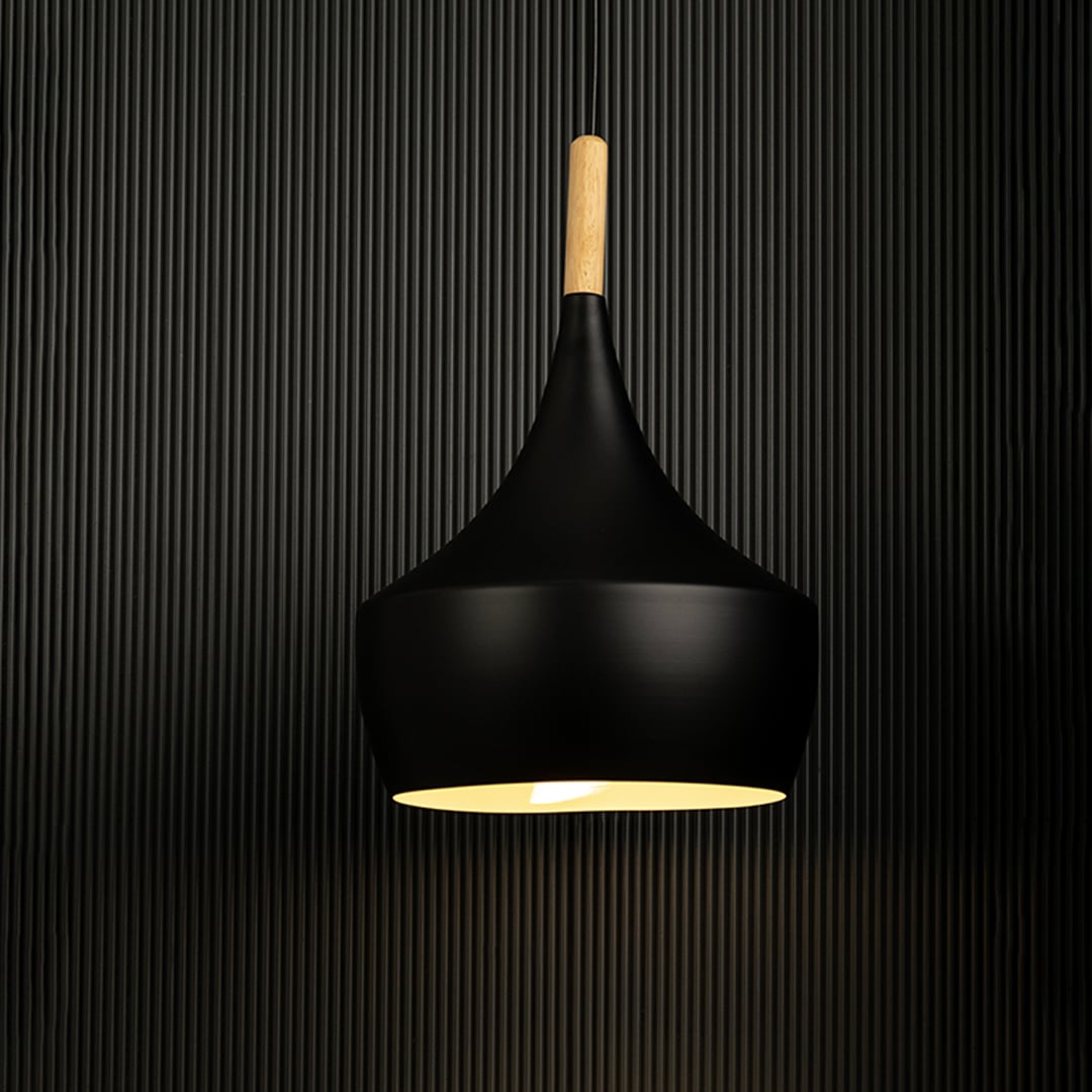 Modern black pendant light illuminated on black background for chic dining room ambiance.