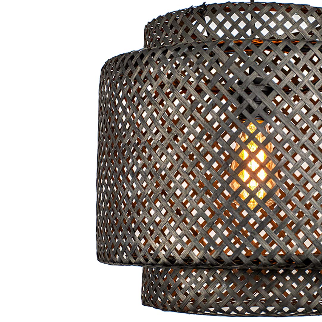 Closeup of handcrafted black rattan hanging lamp showing woven detailing and warm interior light effect.