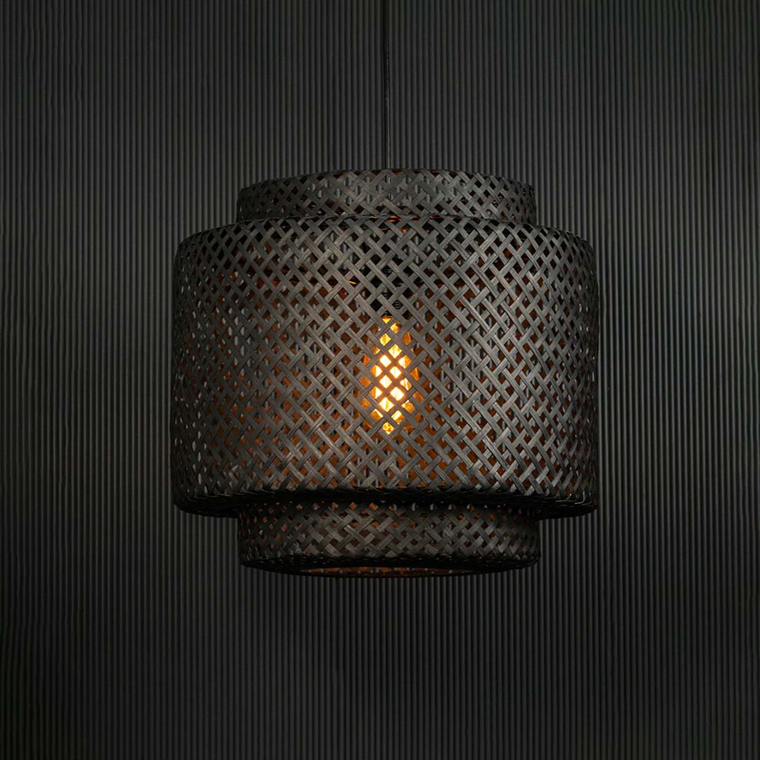 Stylish black rattan lamp glowing warmly on dark background creating elegant ambience for living space decor.
