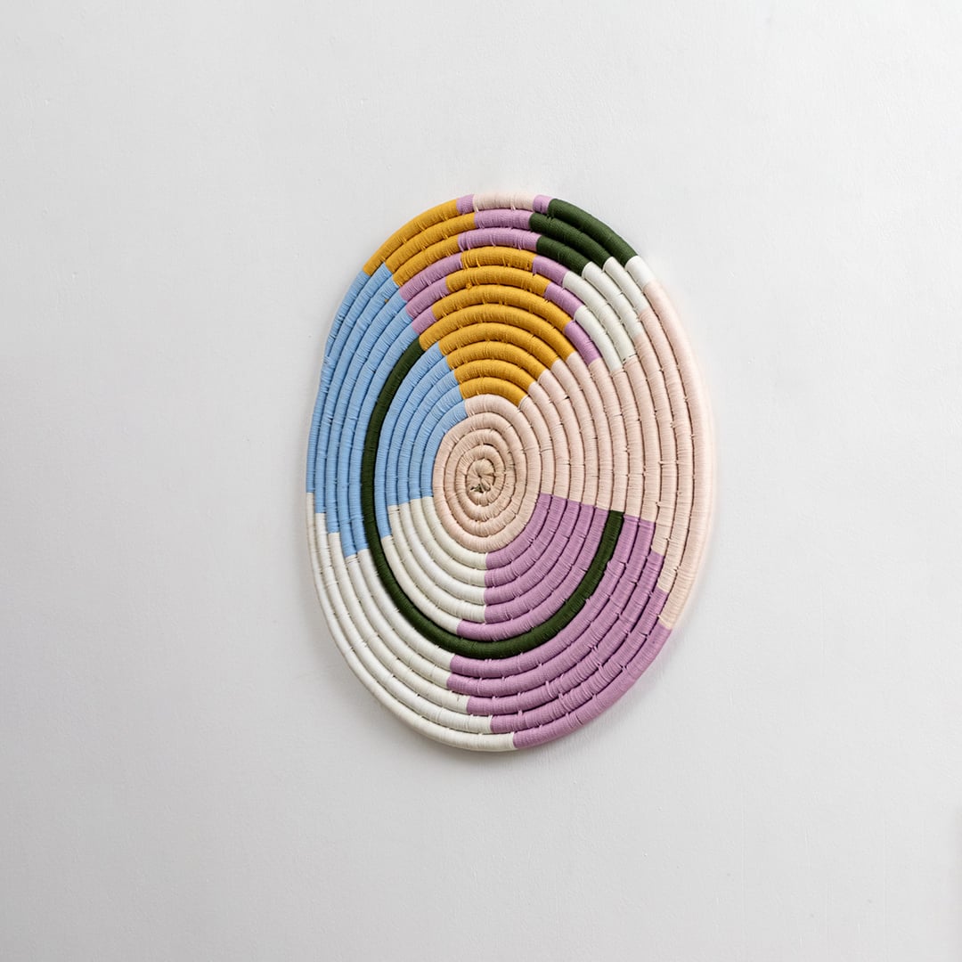 Pastel multicolor cotton wall plate in blue pink mustard green and cream shades shown from a side angle for detailed modern handcrafted decorative wall styling.