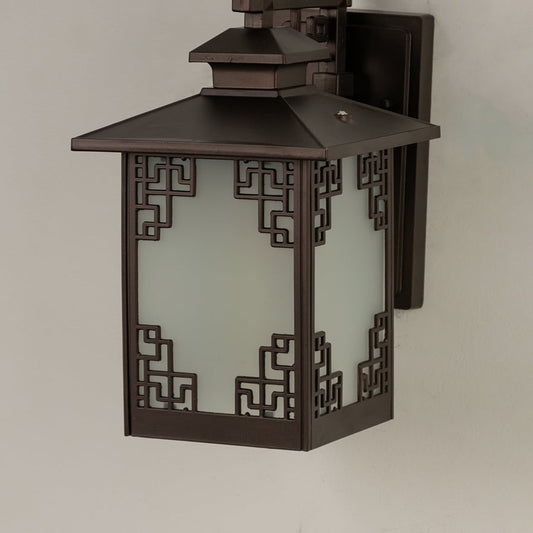 Closeup of brown metal outdoor lantern showing warm glowing frosted glass and detailed geometric frame for elegant entrance and patio lighting.