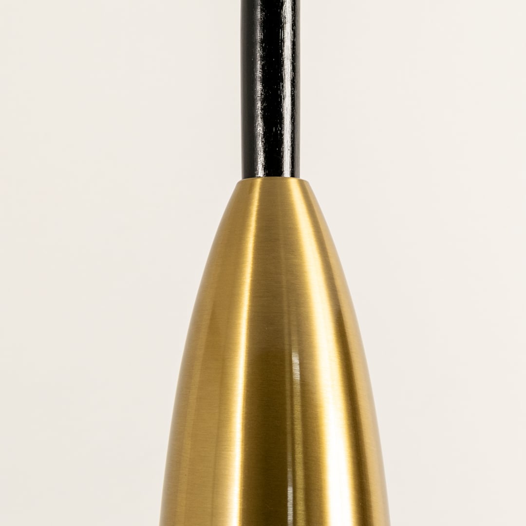 A closeup view of a slim brass pendant light with soft warm illumination shown against a clean white background highlighting its refined texture and minimal décor.