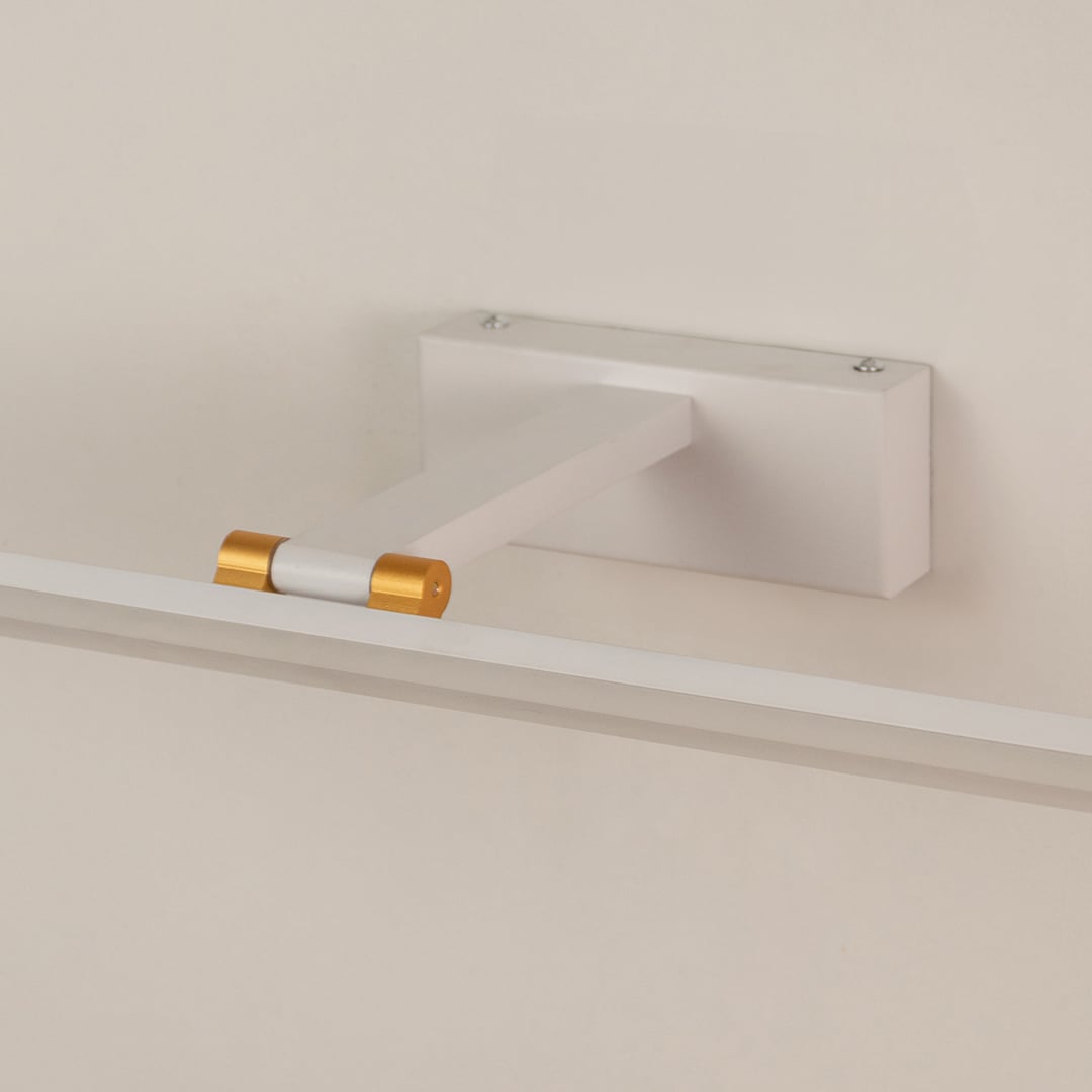 Closeup of white and gold metal picture light showing slim bar design smooth finish and warm directional illumination.