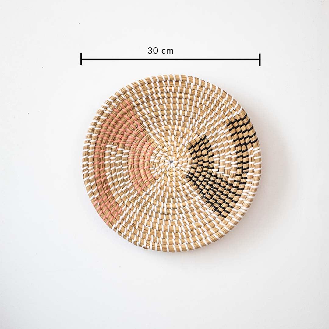 Handwoven wall basket decor in natural pink and black fiber shown with 30cm diameter for decorative wall use.