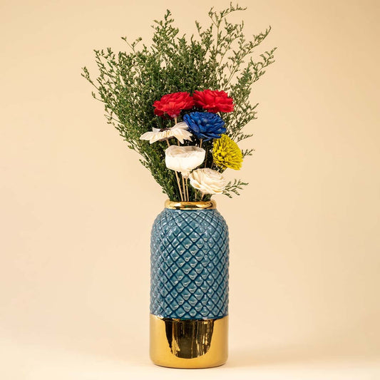 Blue textured vase with bright mixed flowers displayed against a soft beige background creating a warm and vibrant decorative look.