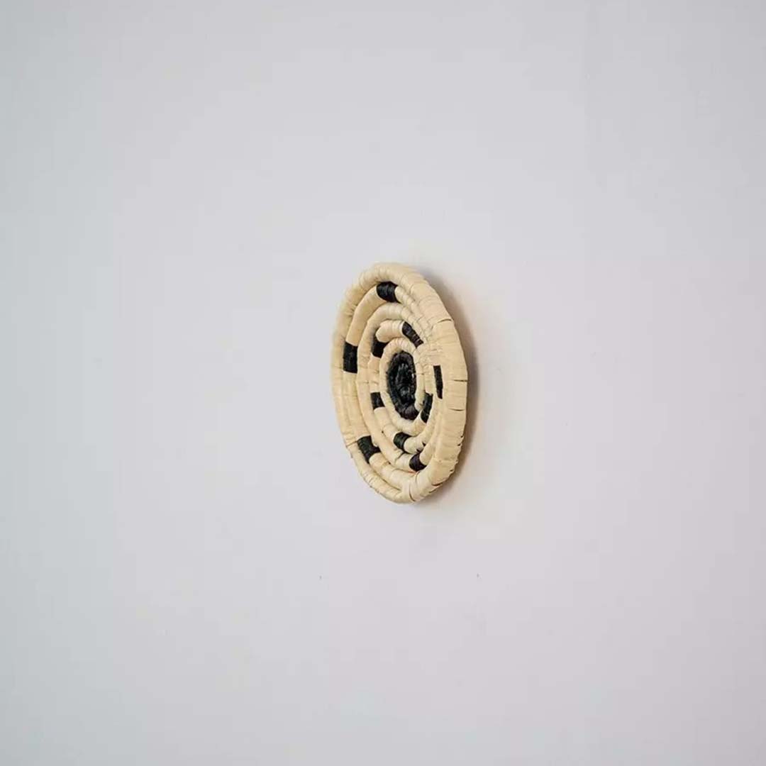 Side profile of handwoven bamboo wall plate in yellow beige shades highlighting detailed weave and natural texture.