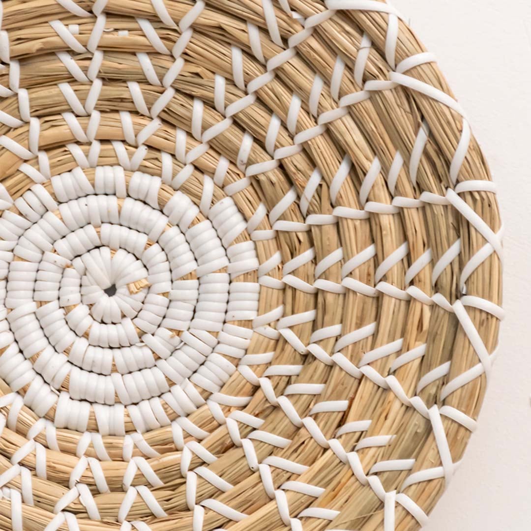 Closeup of handwoven wall plate with natural beige and white spiral pattern for rustic modern interiors.