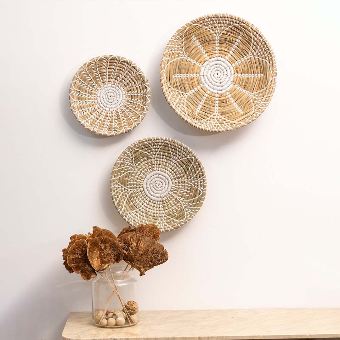 Set of handwoven wall plates in natural beige with white patterns styled above table for modern home decor.