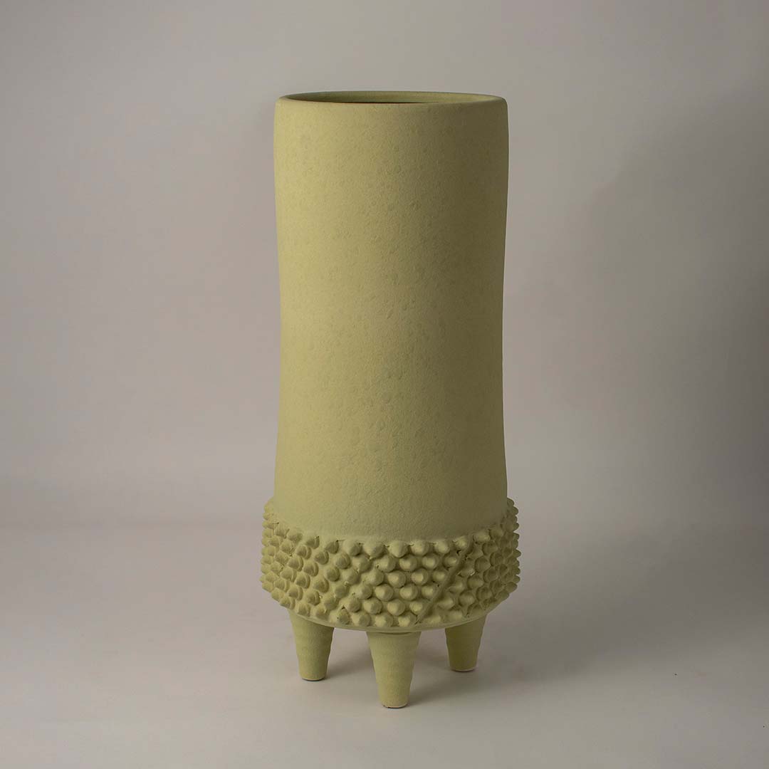 Modern green ceramic vase with dotted texture and matte surface on clean white background reflecting minimal decor style.