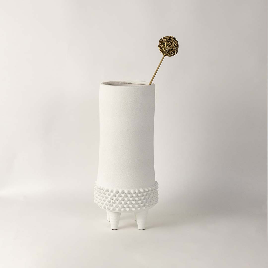 White ceramic textured vase with raised dot pattern placed in modern living room setting for elegant home decoration.