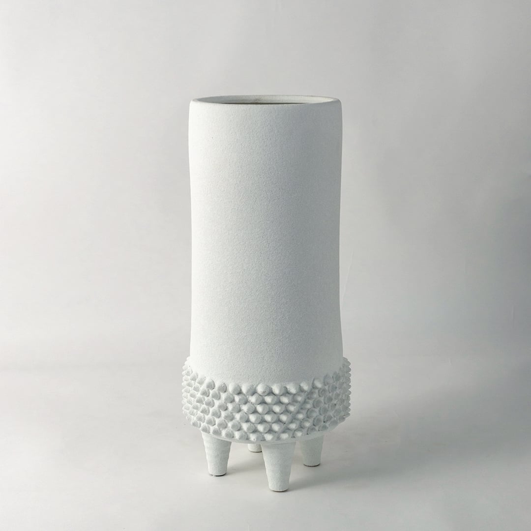 Elegant tall white ceramic vase with dotted base design captured on white background for contemporary home decoration.