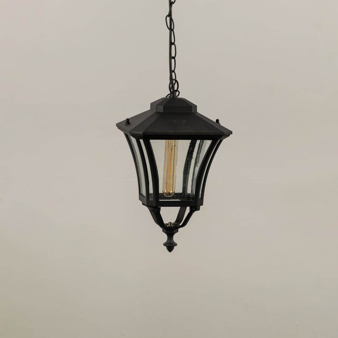 Black hanging lantern on white background with light off displaying its curved metal frame and textured clear glass suitable for outdoor ceiling lighting.