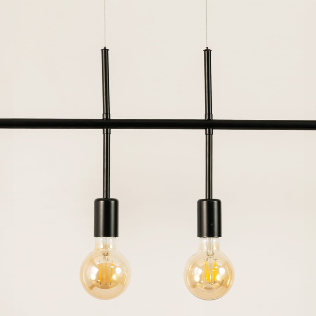 Closeup of black metal linear chandelier showing slim bar frame exposed bulbs and contemporary refined detailing.