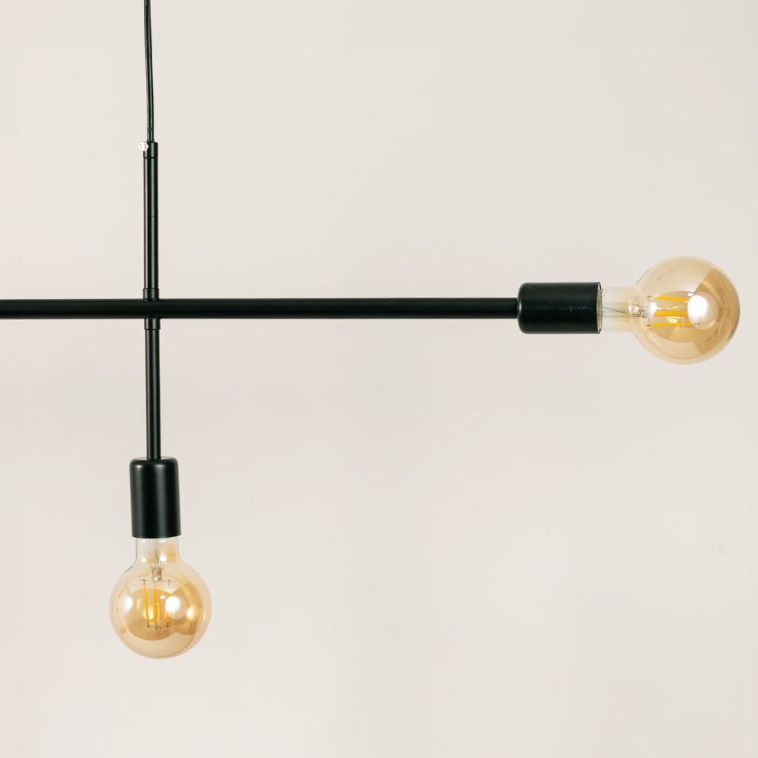 Detailed closeup of black linear chandelier showing matte metal finish bulb holders and smooth streamlined structure.