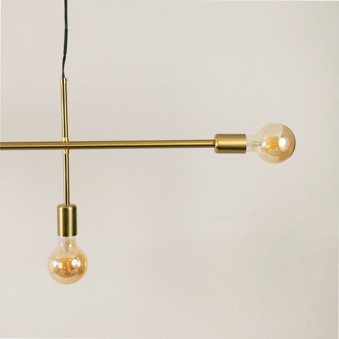 Closeup of gold metal linear chandelier showing slim bar frame exposed bulbs and refined contemporary detailing.