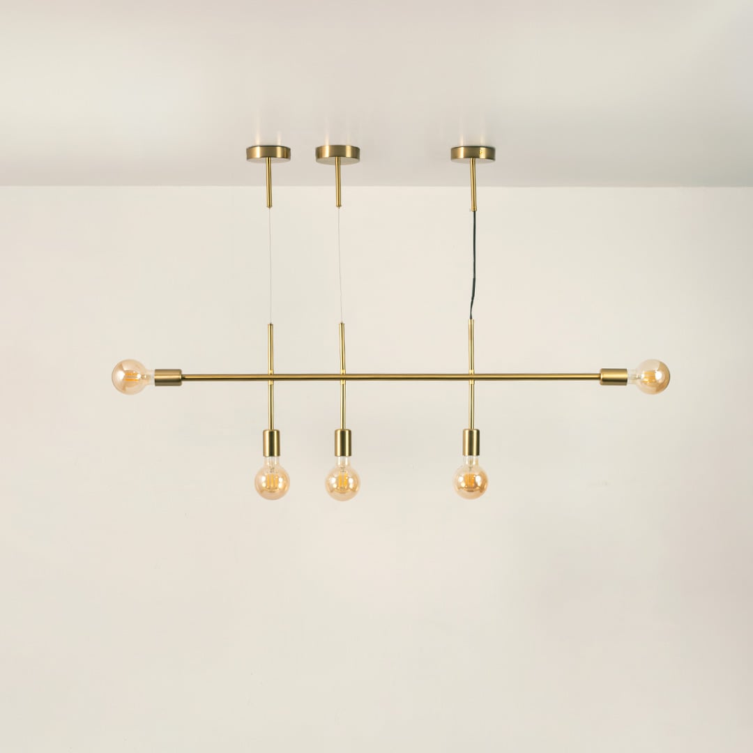 Gold metal linear chandelier on a white background with lights off highlighting its elegant minimal silhouette.