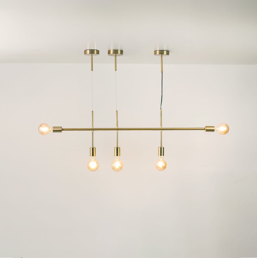 Gold linear chandelier with glowing globe bulbs on a clean white background showcasing its sleek minimal modern design.