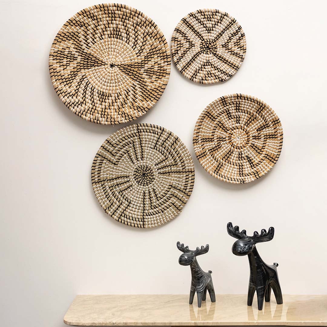 Woven wall basket displayed on a living room wall above a marble table with decorative figurines adding rustic and artisanal charm.