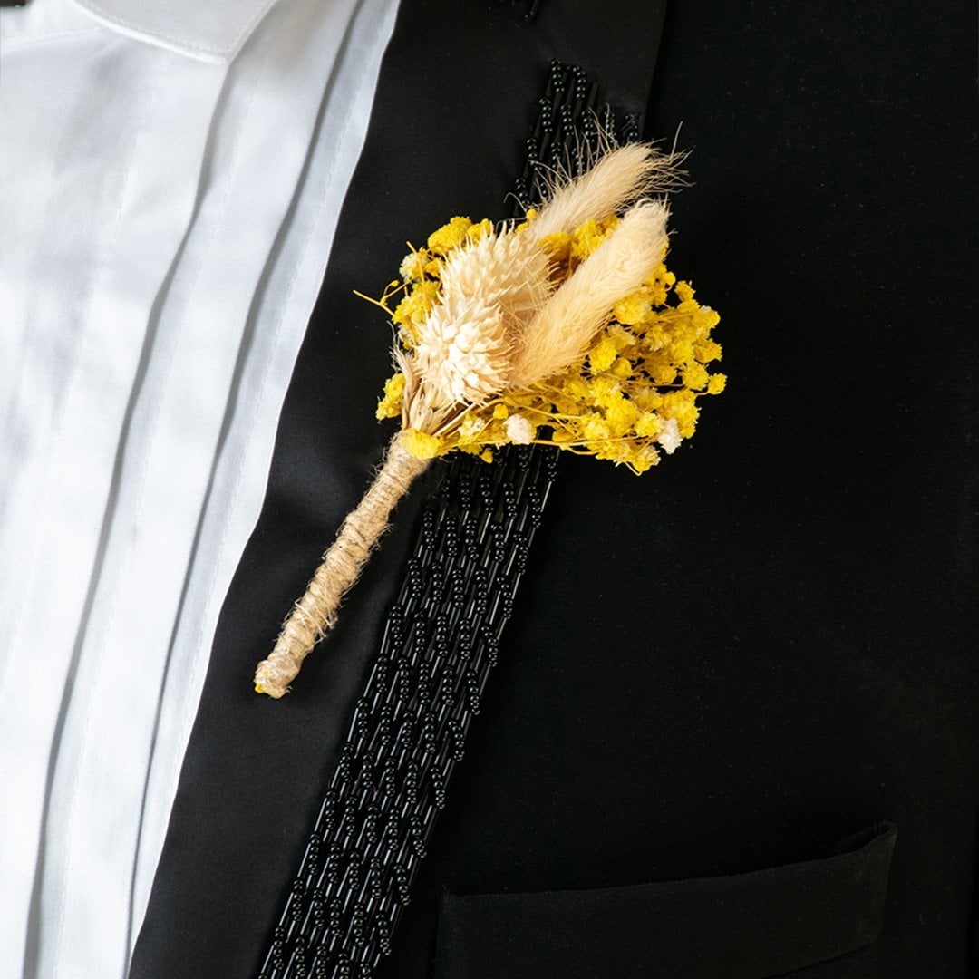 Closeup of yellow dried flower boutonniere with preserved stems and rustic jute wrap – artificial wedding flower accessory.