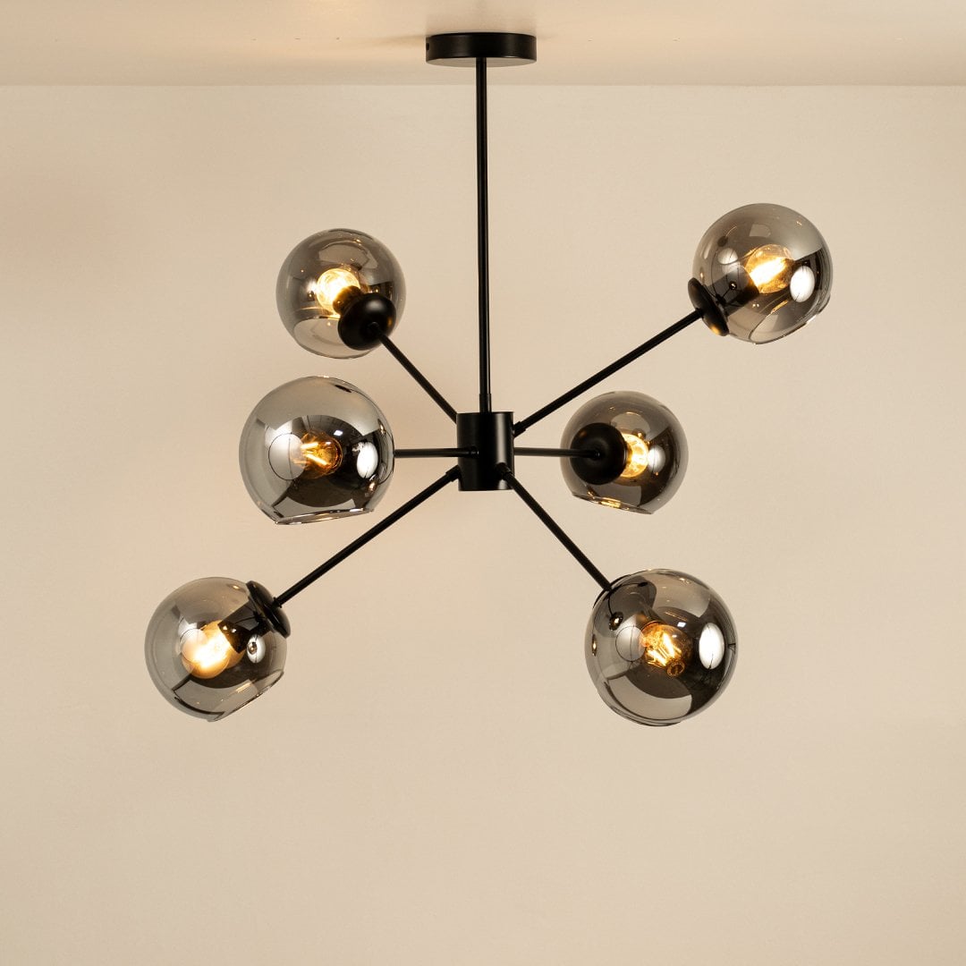 Black metal chandelier with chrome glass globes glowing elegantly on white background showcasing artistic design for home interiors.