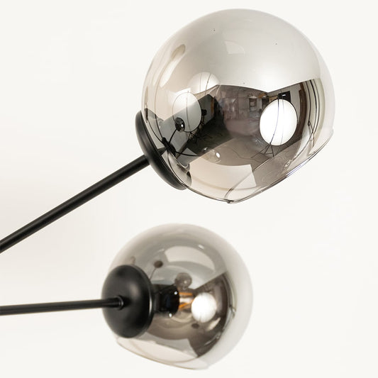 Close view of chrome glass chandelier showing smooth reflective globes black metal rods and sleek modern structural detailing.