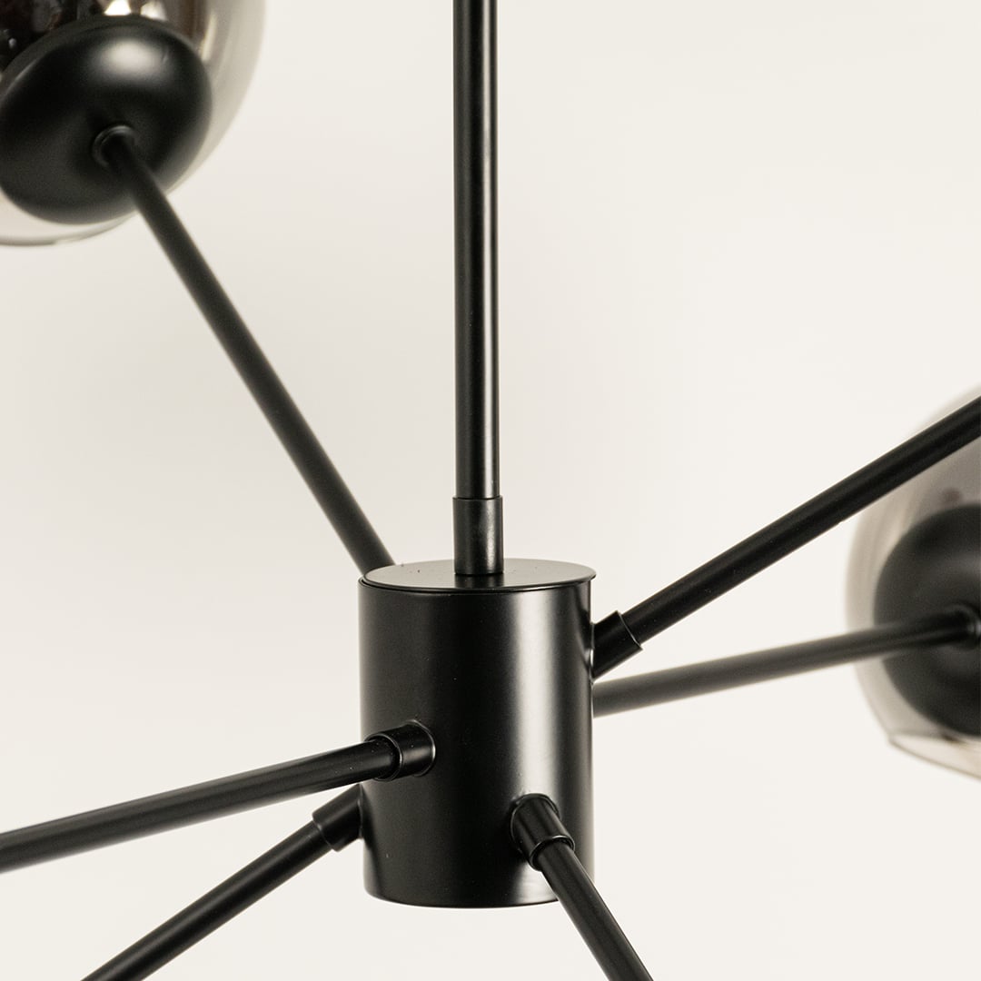 Close view of chrome glass chandelier showing smooth reflective detail of globes black metal rods and sleek modern structural detailing.