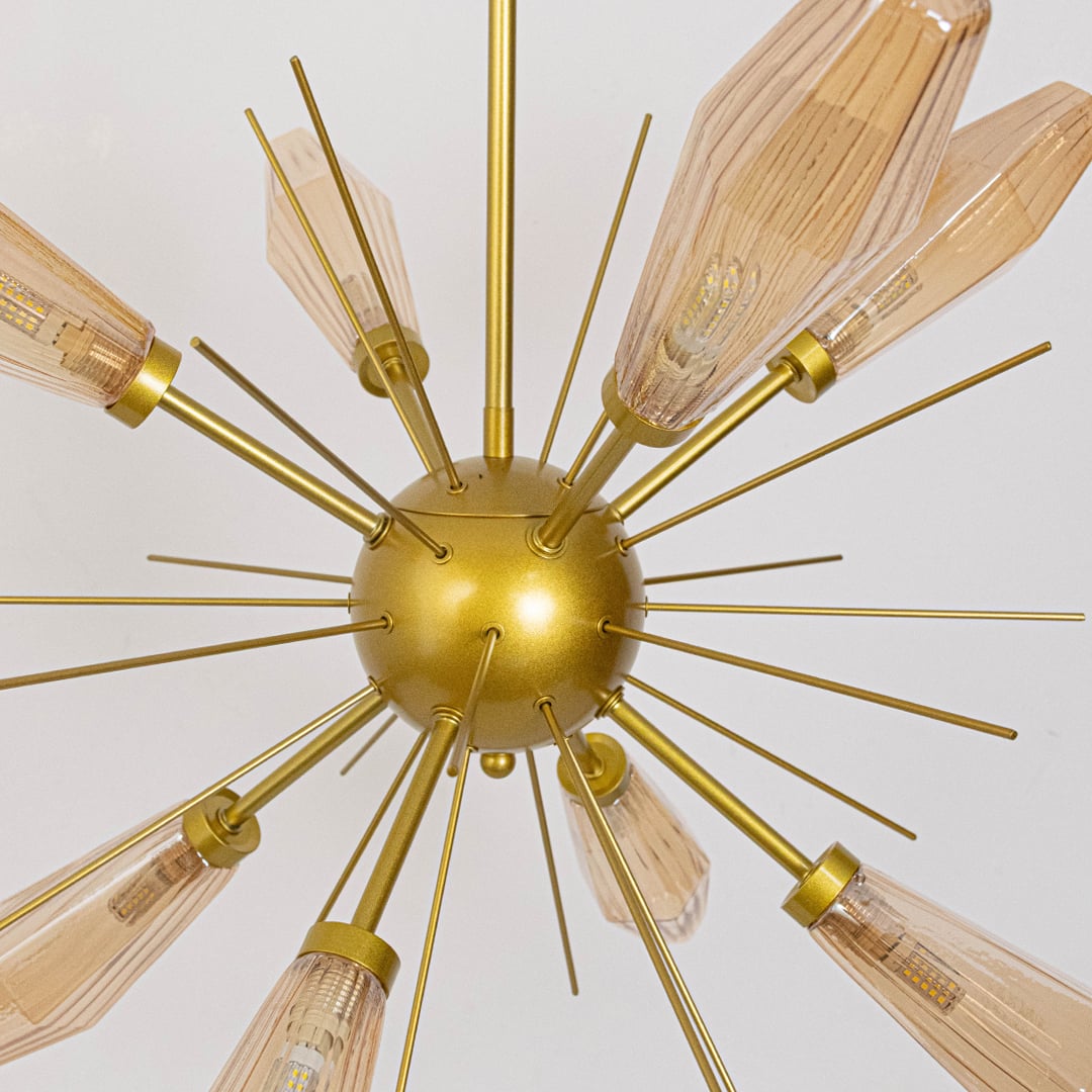 Closeup of golden metal chandelier with amber glass shades showing fine detailing and premium finish for modern ceiling decor.