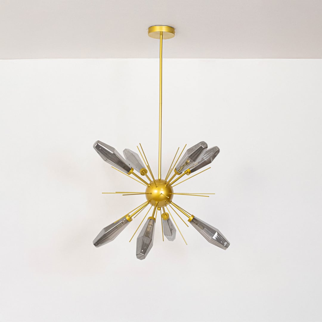 Gold chandelier unlit against white background emphasizing geometric design  crystal glass rods  and polished gold texture.