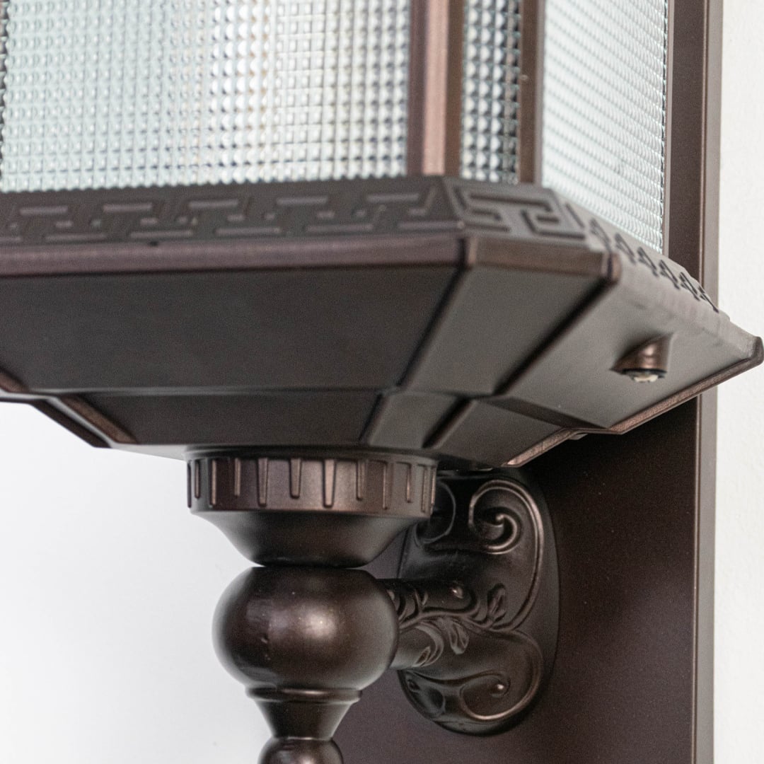 Closeup of outdoor wall lantern underside showing metal roof structure decorative mounting arm and sturdy exterior lighting build.