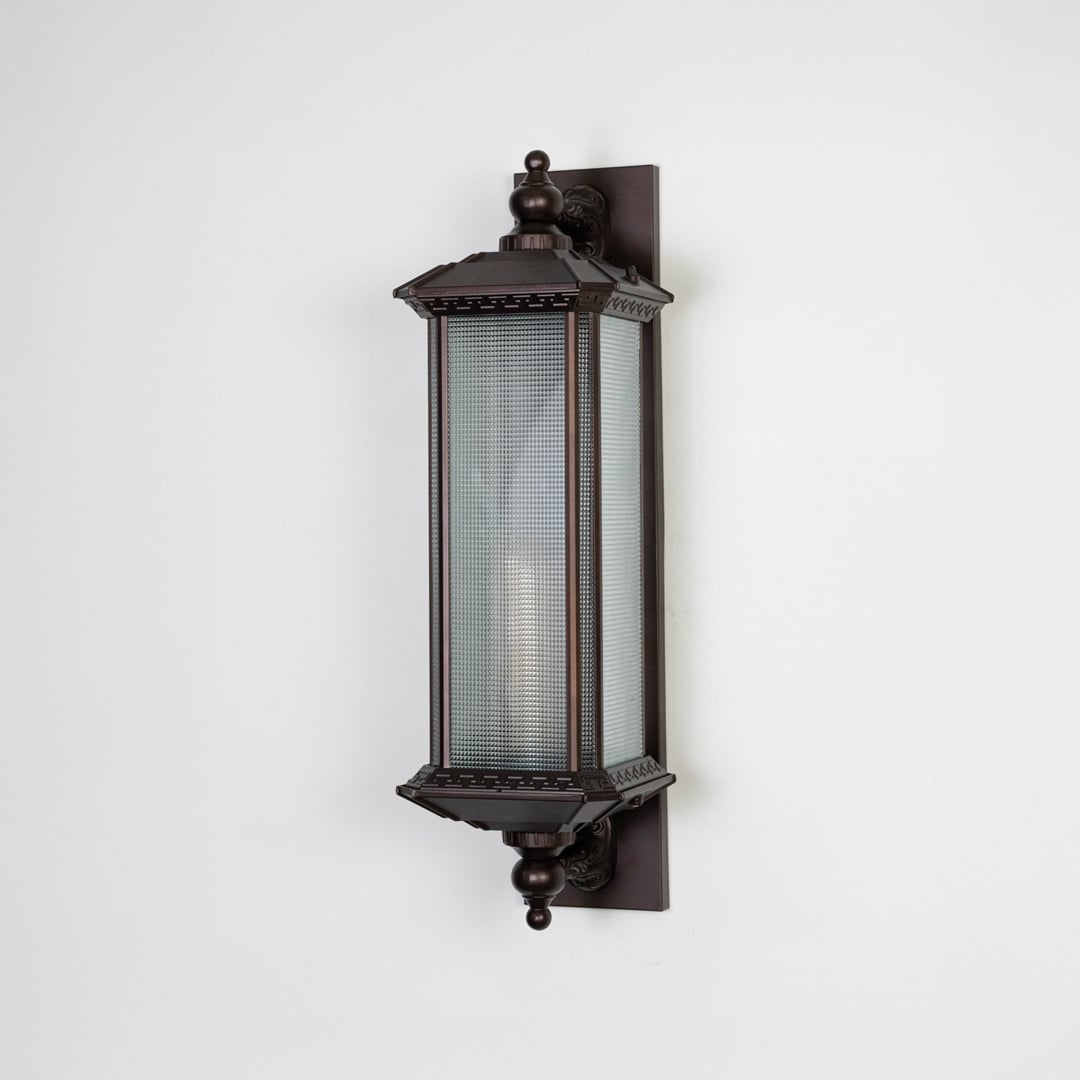 Vintage bronze wall lantern with frosted glass shade displayed off on plain white background.